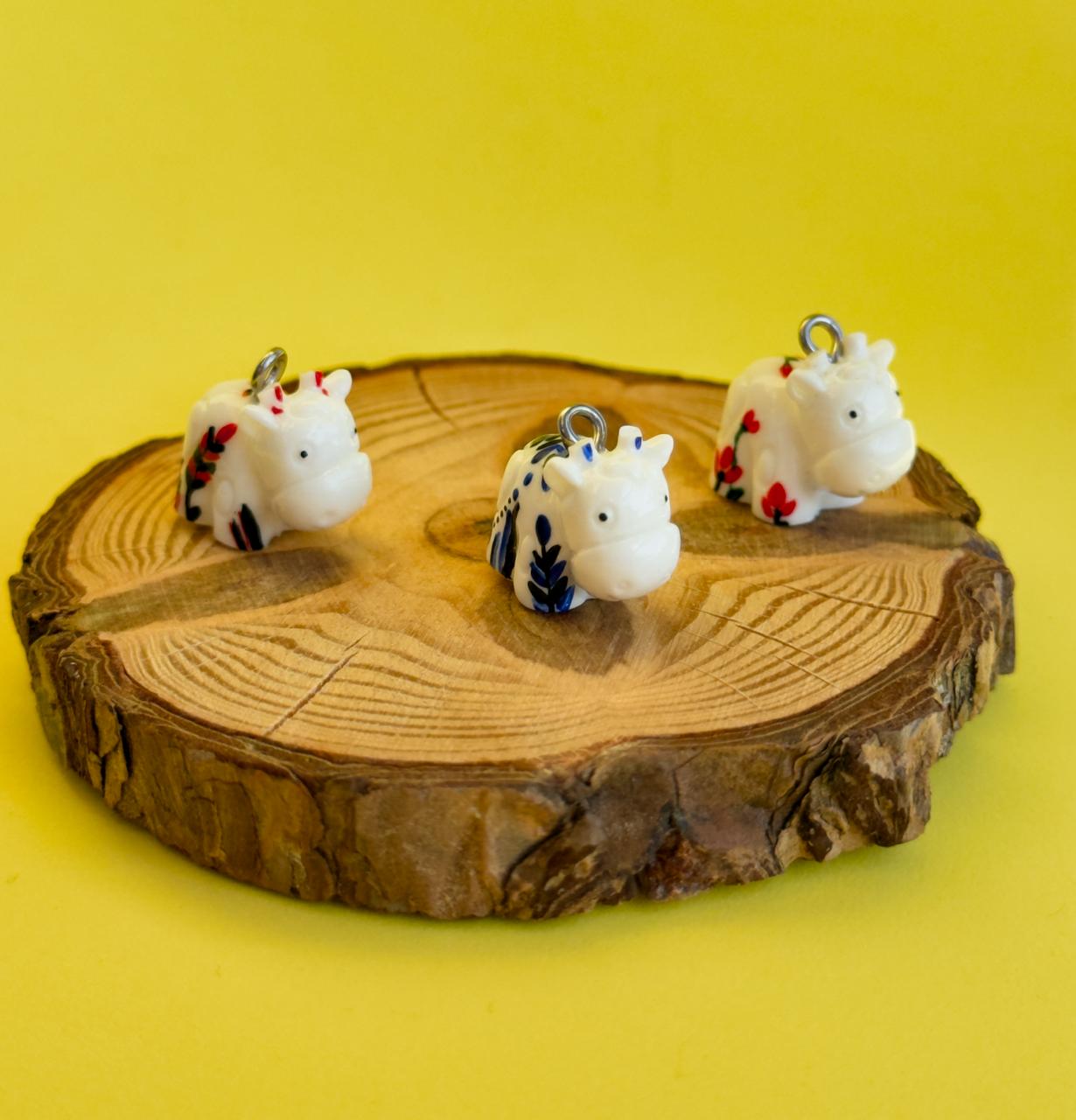 All pendants feature a miniature cow and are hand-painted.